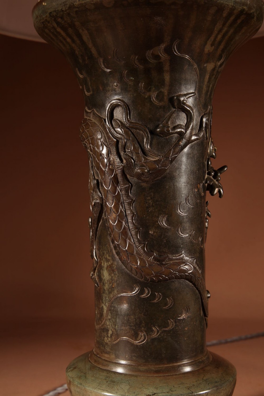 A dark patinated Japanese bronze table lamp featuring a relief-carved dragon wrapped around the central column, topped with a cream pleated lampshade. View VI