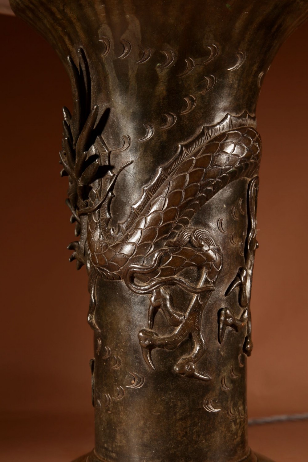 A dark patinated Japanese bronze table lamp featuring a relief-carved dragon wrapped around the central column, topped with a cream pleated lampshade. View VII