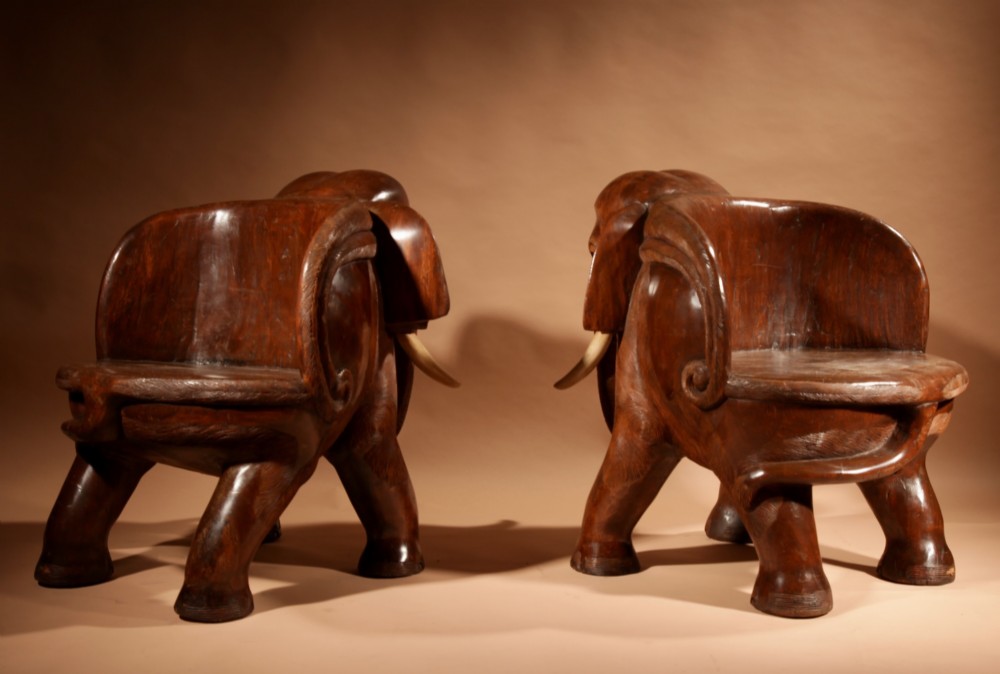 A pair of heavy hand-carved wooden armchairs sculpted in the form of standing elephants with textured hides and light-coloured tusks. View V