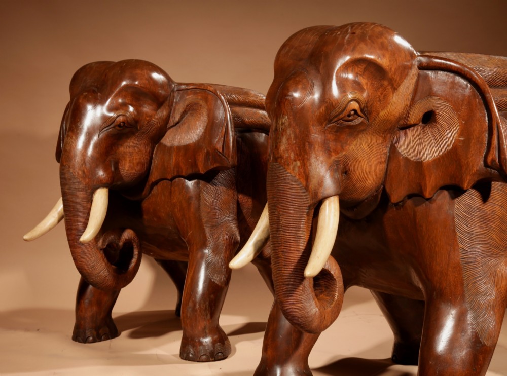 A pair of heavy hand-carved wooden armchairs sculpted in the form of standing elephants with textured hides and light-coloured tusks. View IX