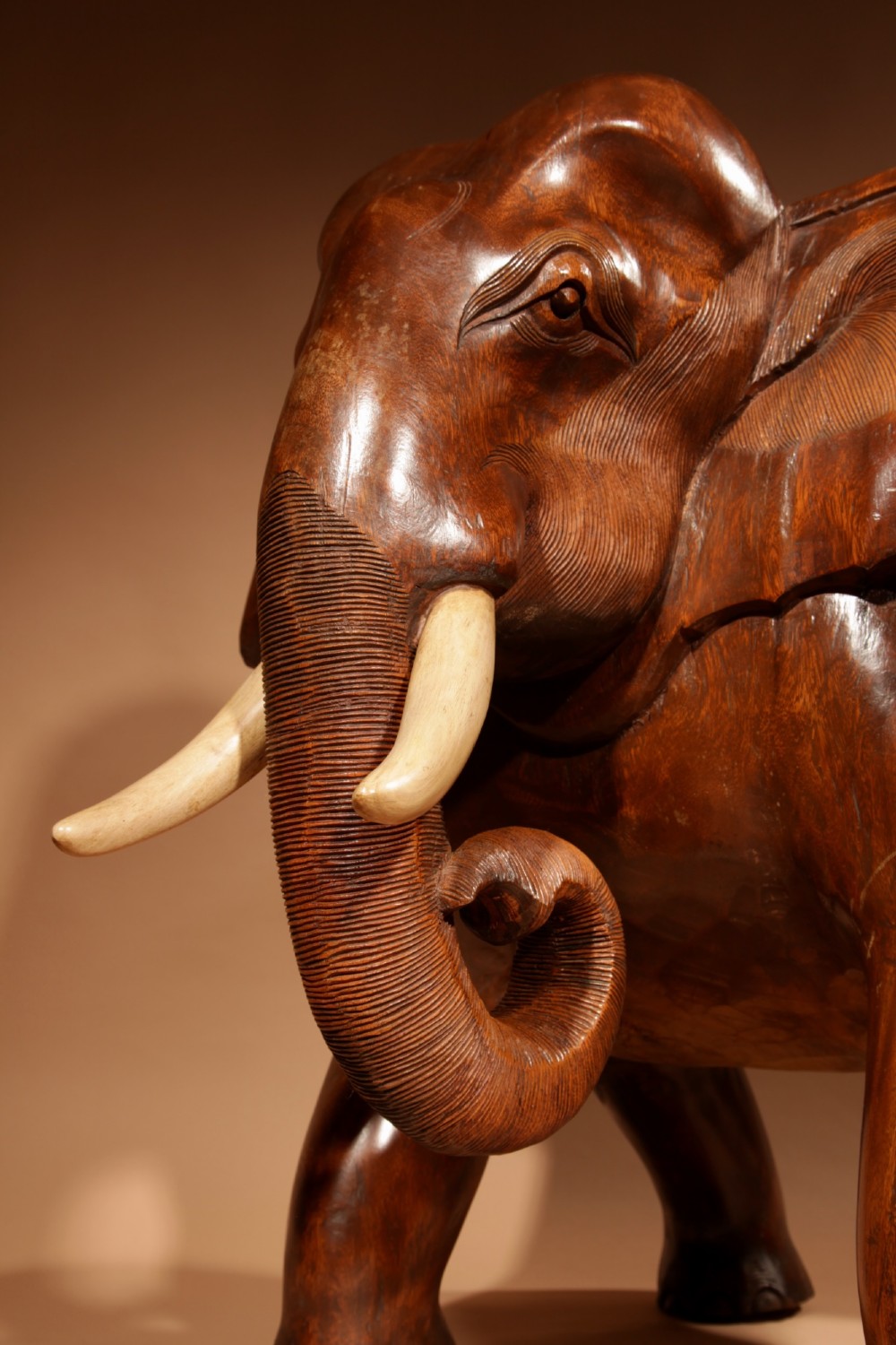 A pair of heavy hand-carved wooden armchairs sculpted in the form of standing elephants with textured hides and light-coloured tusks. View X