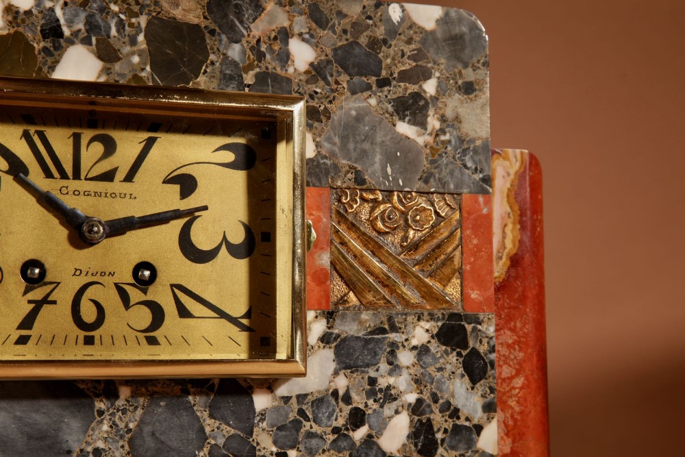 An Art Deco clock garniture set constructed from dark speckled stone and coral marble featuring a central rectangular clock with gilt numerals and two matching side pieces. View IV