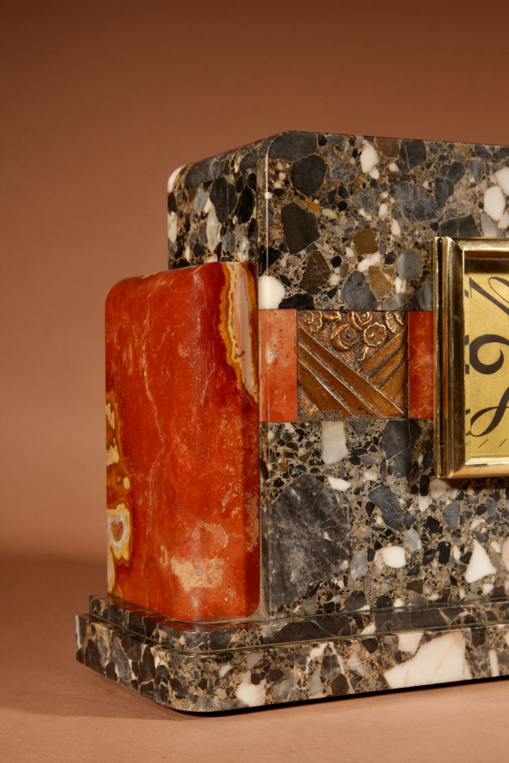 An Art Deco clock garniture set constructed from dark speckled stone and coral marble featuring a central rectangular clock with gilt numerals and two matching side pieces. View V