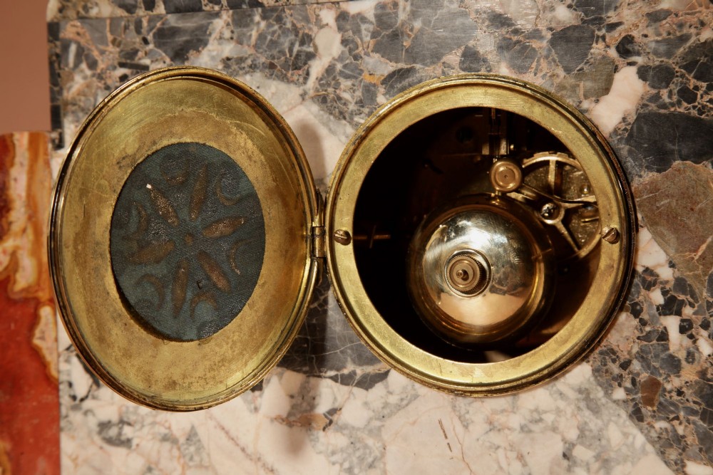 An Art Deco clock garniture set constructed from dark speckled stone and coral marble featuring a central rectangular clock with gilt numerals and two matching side pieces. View VII