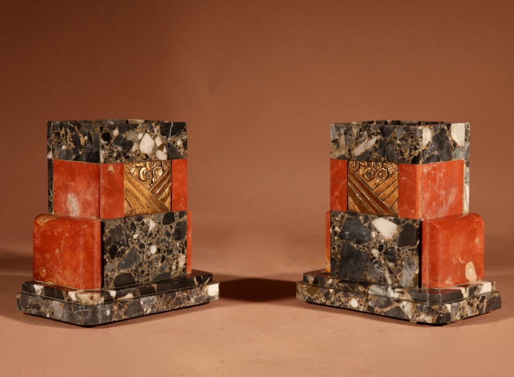 An Art Deco clock garniture set constructed from dark speckled stone and coral marble featuring a central rectangular clock with gilt numerals and two matching side pieces. View IX