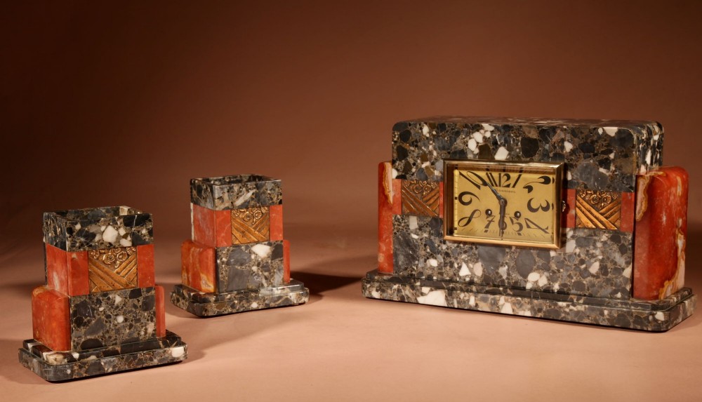 An Art Deco clock garniture set constructed from dark speckled stone and coral marble featuring a central rectangular clock with gilt numerals and two matching side pieces. View XIII