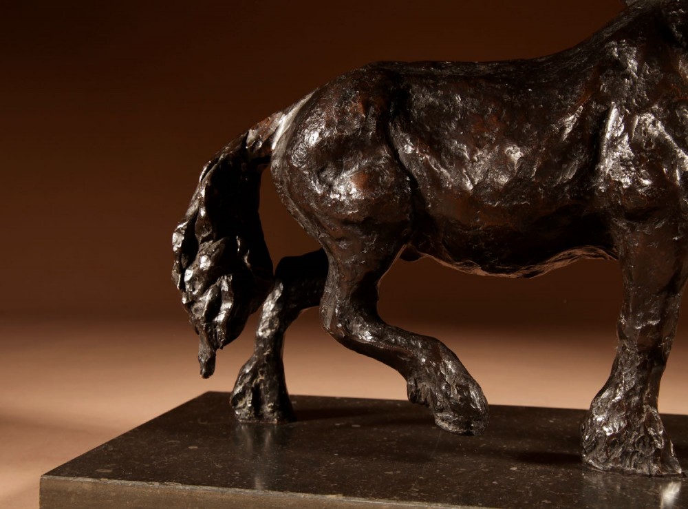 A dark patinated bronze sculpture of a muscular draft horse with one raised foreleg mounted on a rectangular stone base. View IX