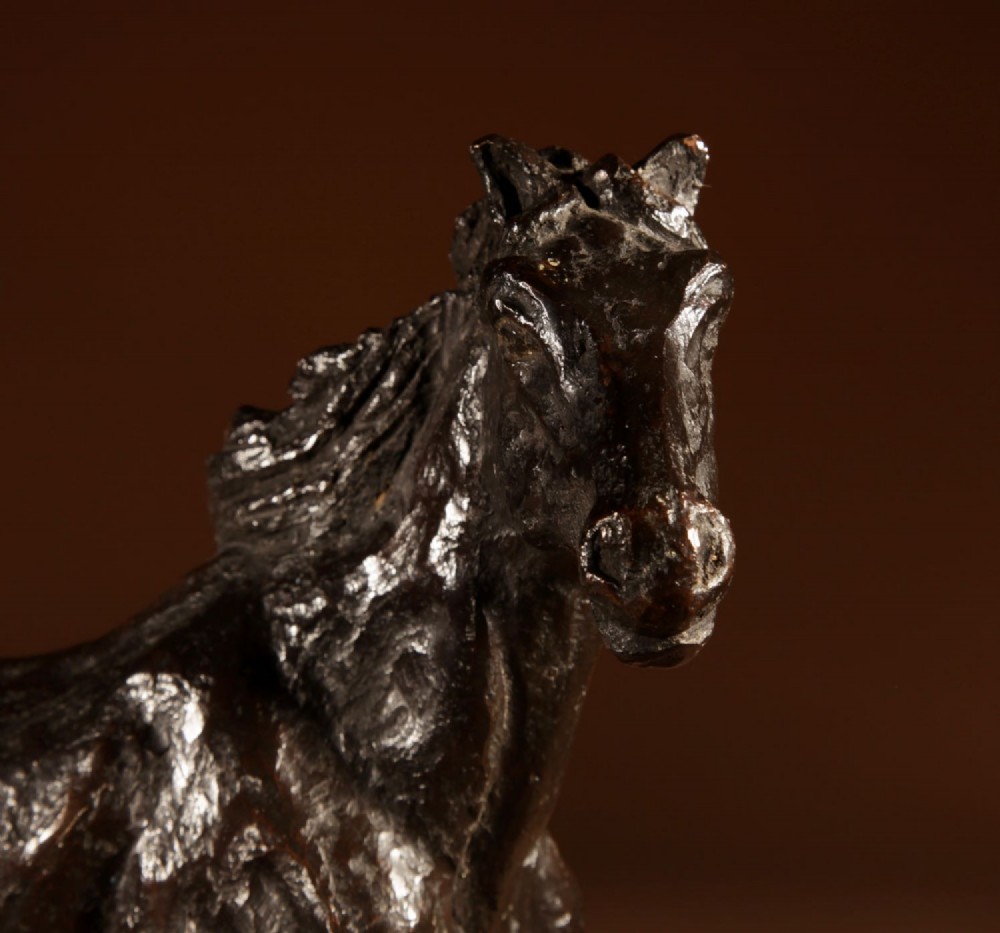 A dark patinated bronze sculpture of a muscular draft horse with one raised foreleg mounted on a rectangular stone base. View X