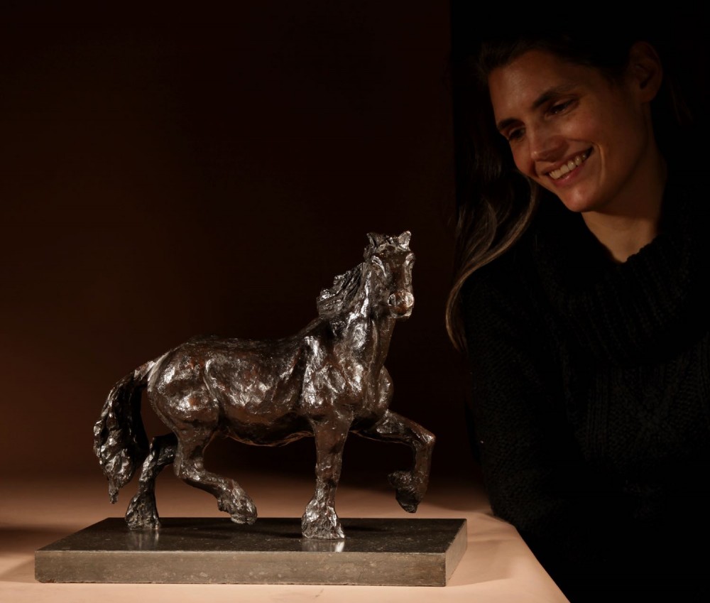 A dark patinated bronze sculpture of a muscular draft horse with one raised foreleg mounted on a rectangular stone base. View XI