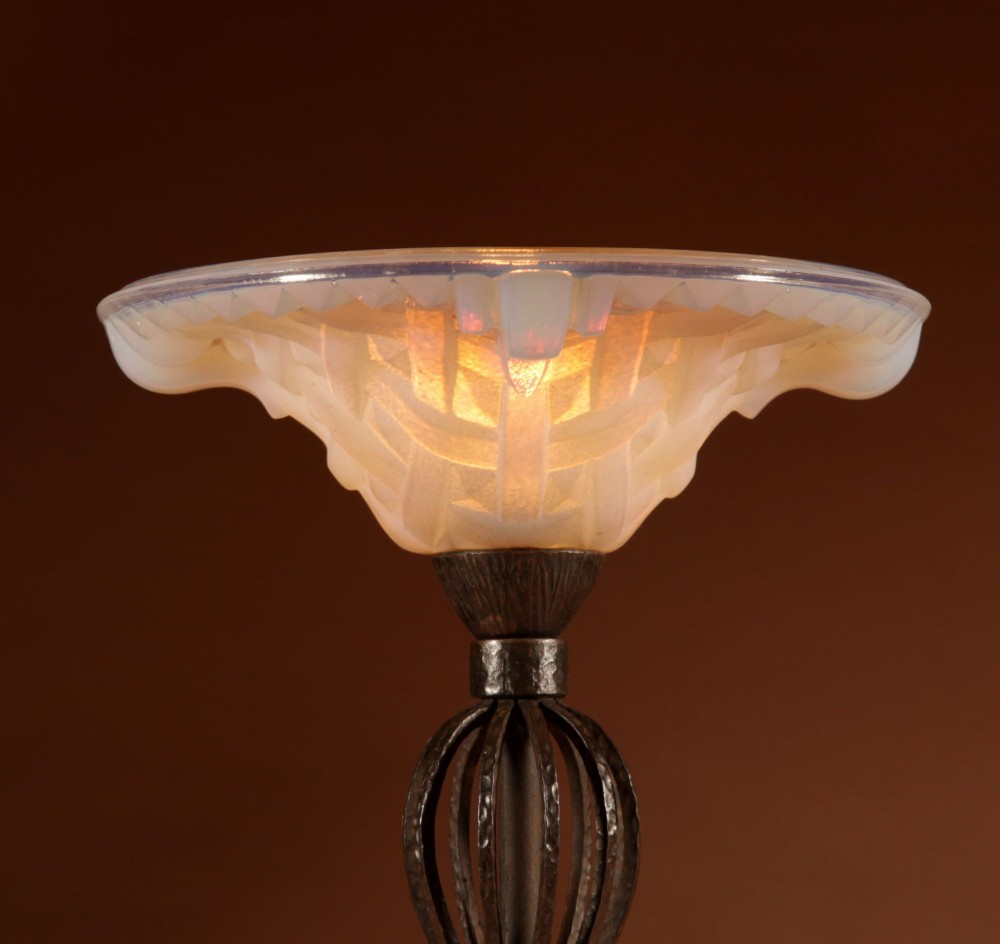 An illuminated French Art Deco table lamp with a flared opalescent glass shade set atop a dark, hammered wrought iron stem and circular base. View V