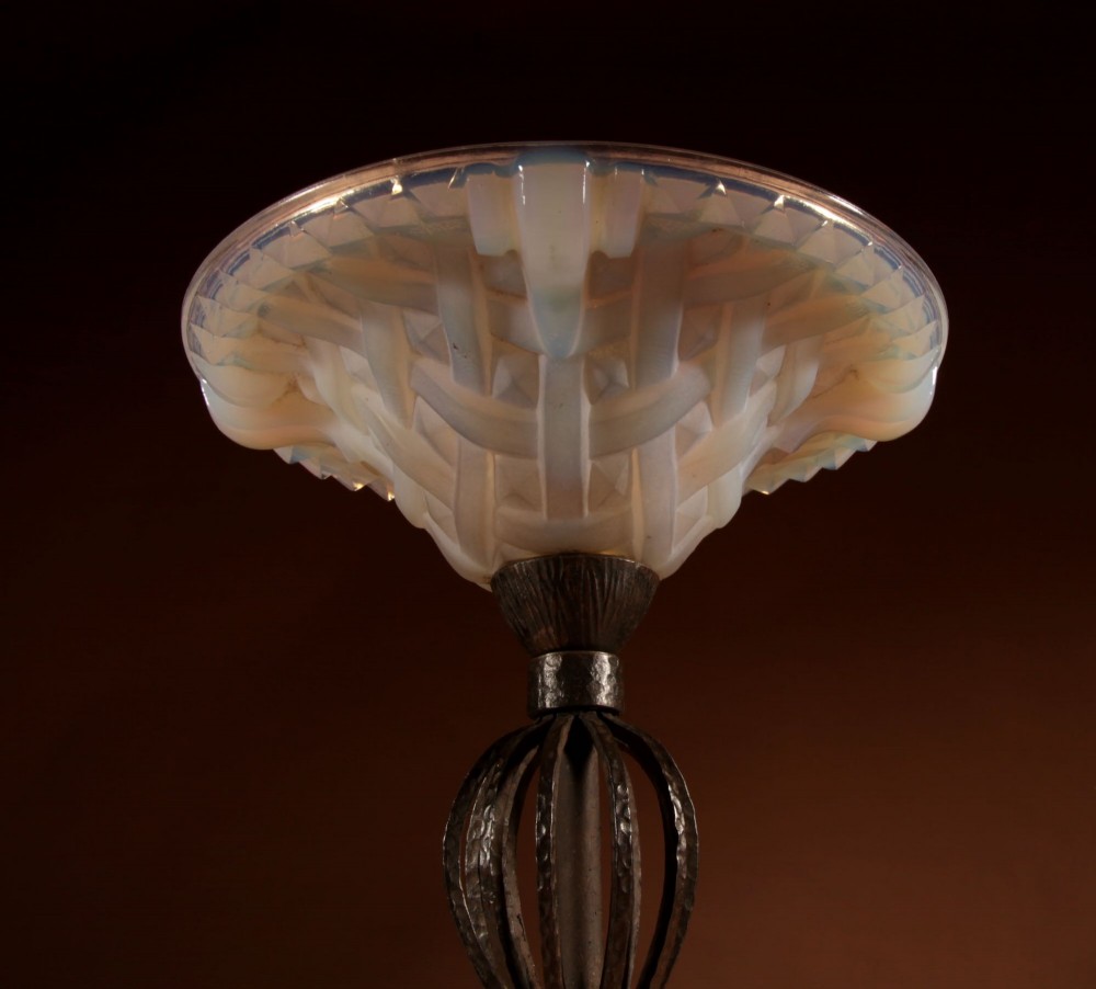 An illuminated French Art Deco table lamp with a flared opalescent glass shade set atop a dark, hammered wrought iron stem and circular base. View IX
