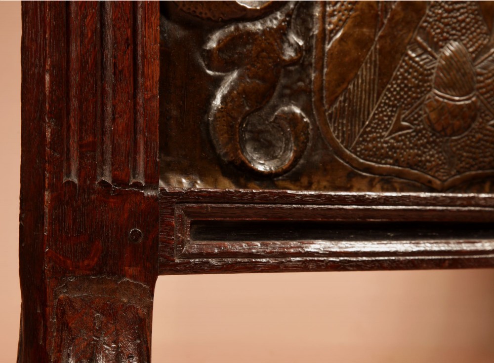 An antique dark oak fire screen featuring a central chased brass panel depicting a coat of arms with an eagle and acorns. View V