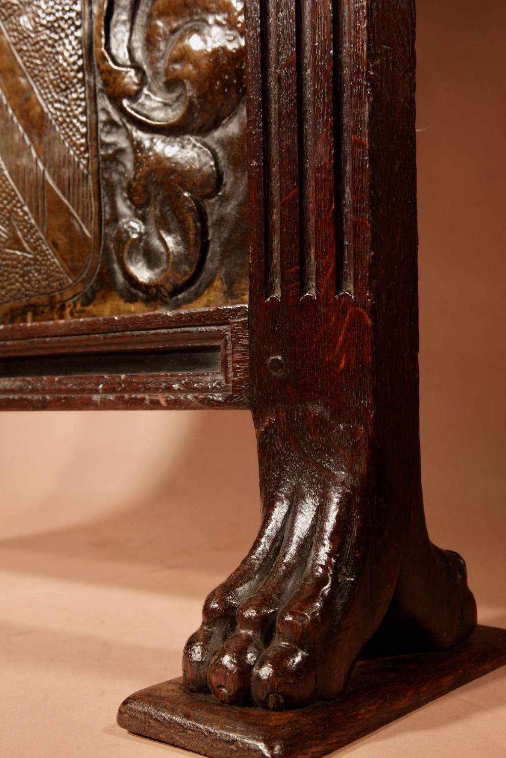 An antique dark oak fire screen featuring a central chased brass panel depicting a coat of arms with an eagle and acorns. View VI