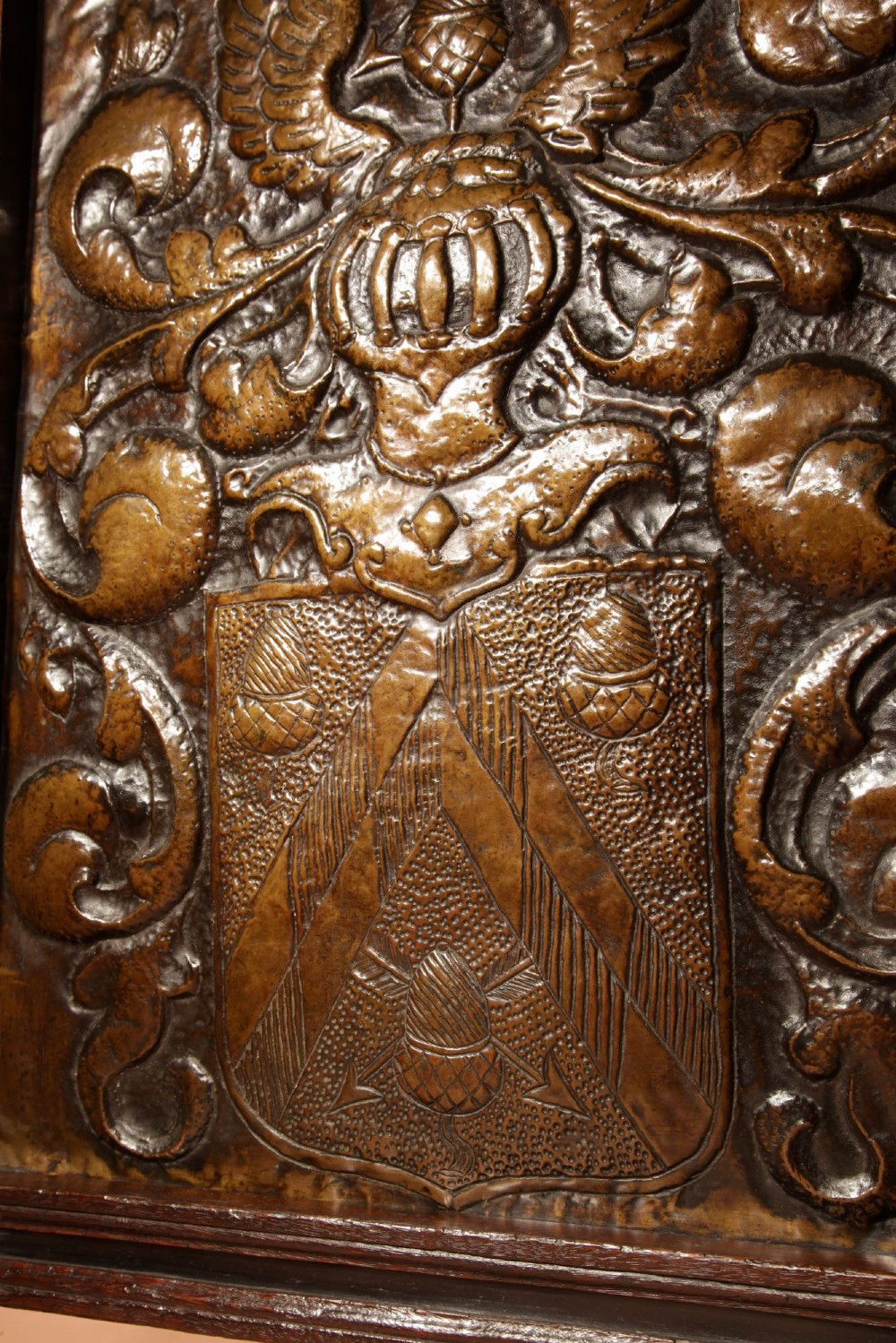 An antique dark oak fire screen featuring a central chased brass panel depicting a coat of arms with an eagle and acorns. View VII