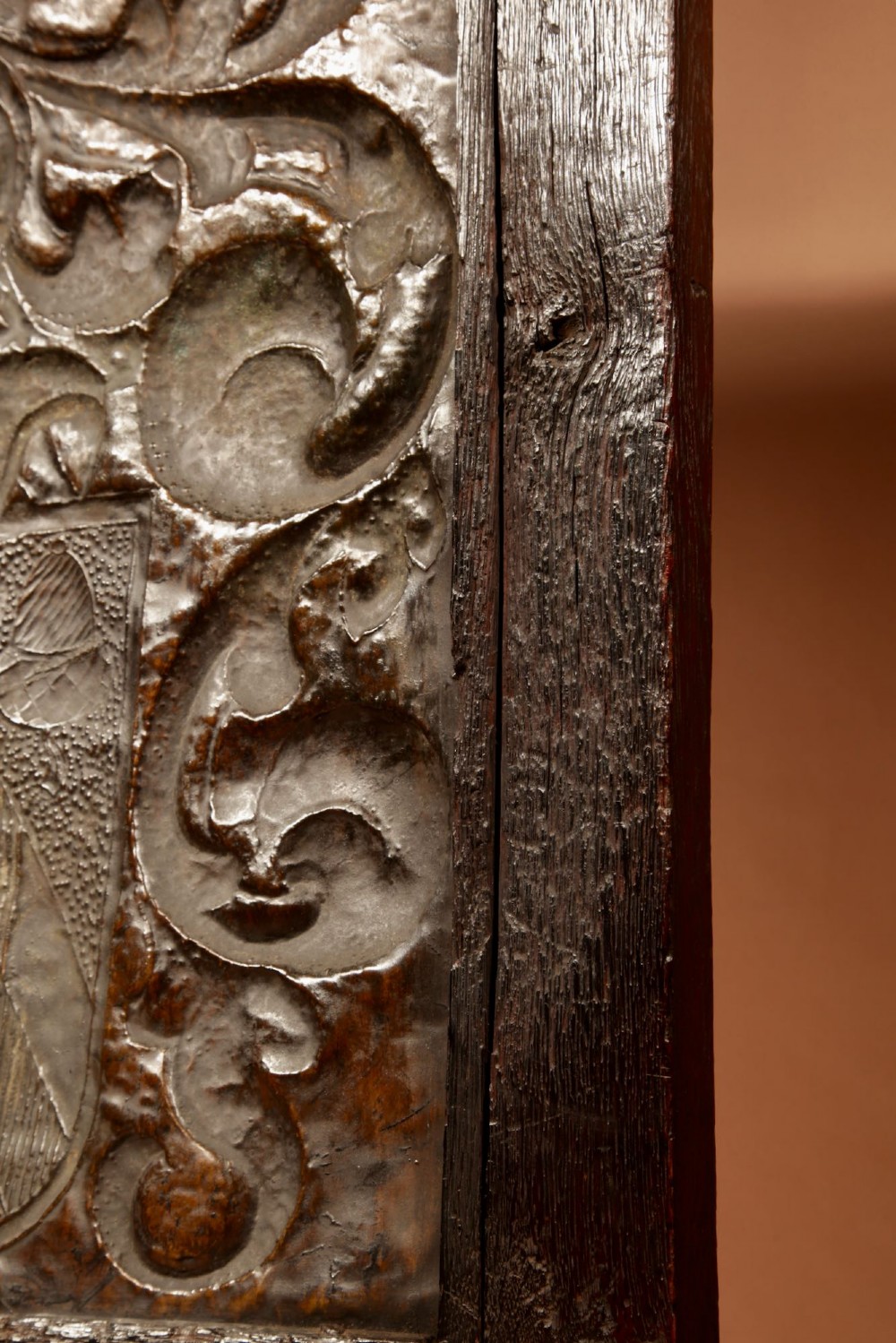An antique dark oak fire screen featuring a central chased brass panel depicting a coat of arms with an eagle and acorns. View X