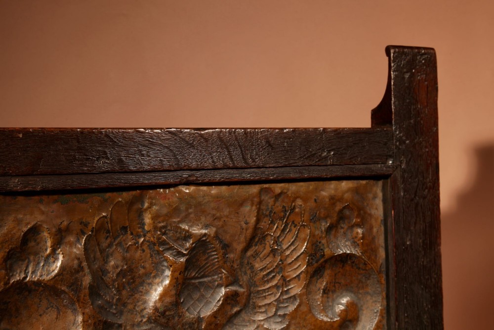 An antique dark oak fire screen featuring a central chased brass panel depicting a coat of arms with an eagle and acorns. View XII