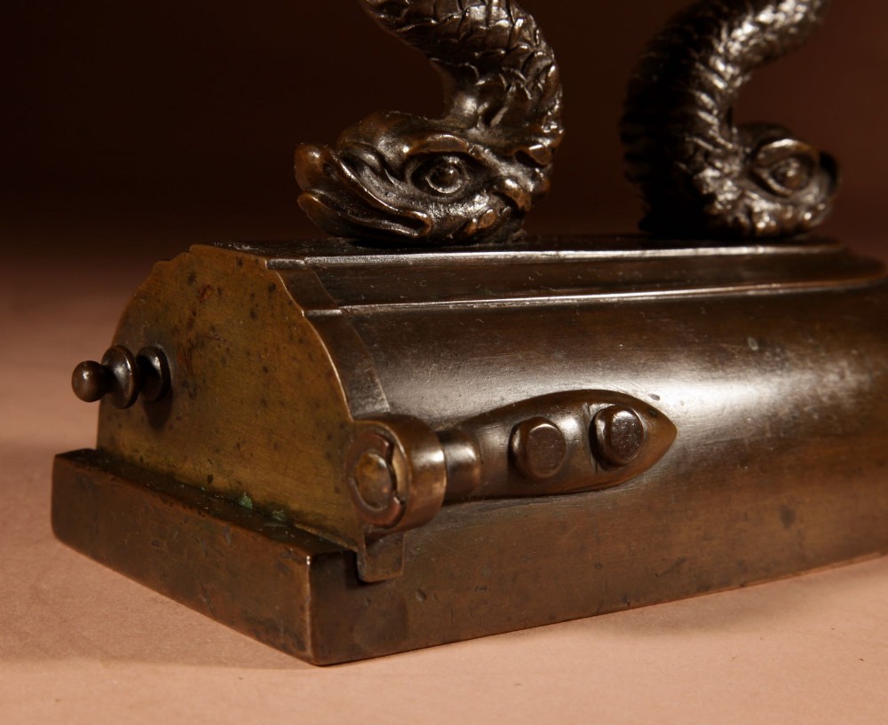 A nineteenth-century French bronze flat iron featuring twin dolphin-shaped supports, a cane-wrapped handle, and a rear door mechanism. View VI