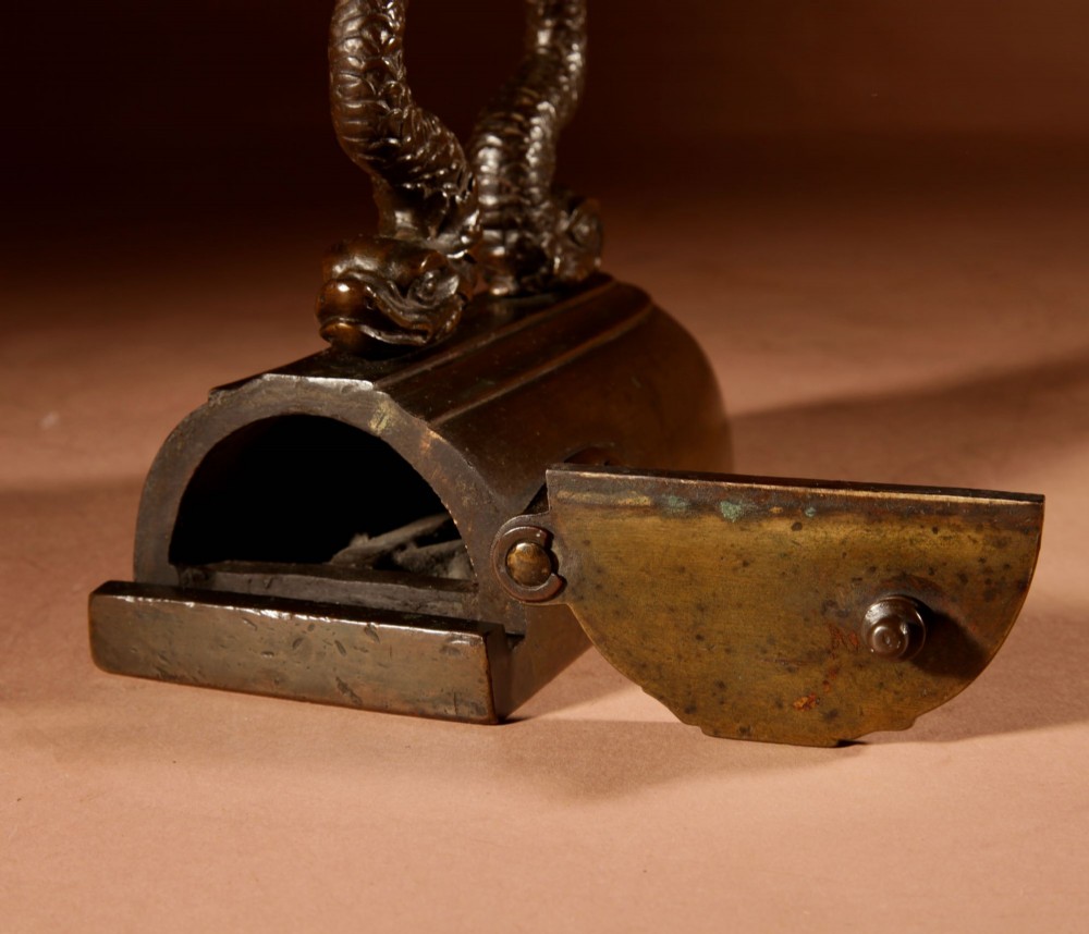 A nineteenth-century French bronze flat iron featuring twin dolphin-shaped supports, a cane-wrapped handle, and a rear door mechanism. View VII
