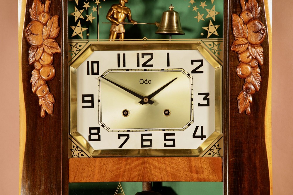 An Art Deco carved walnut wall clock by Odo featuring a brass automaton bell striker and a Venetian glass lower window. View III