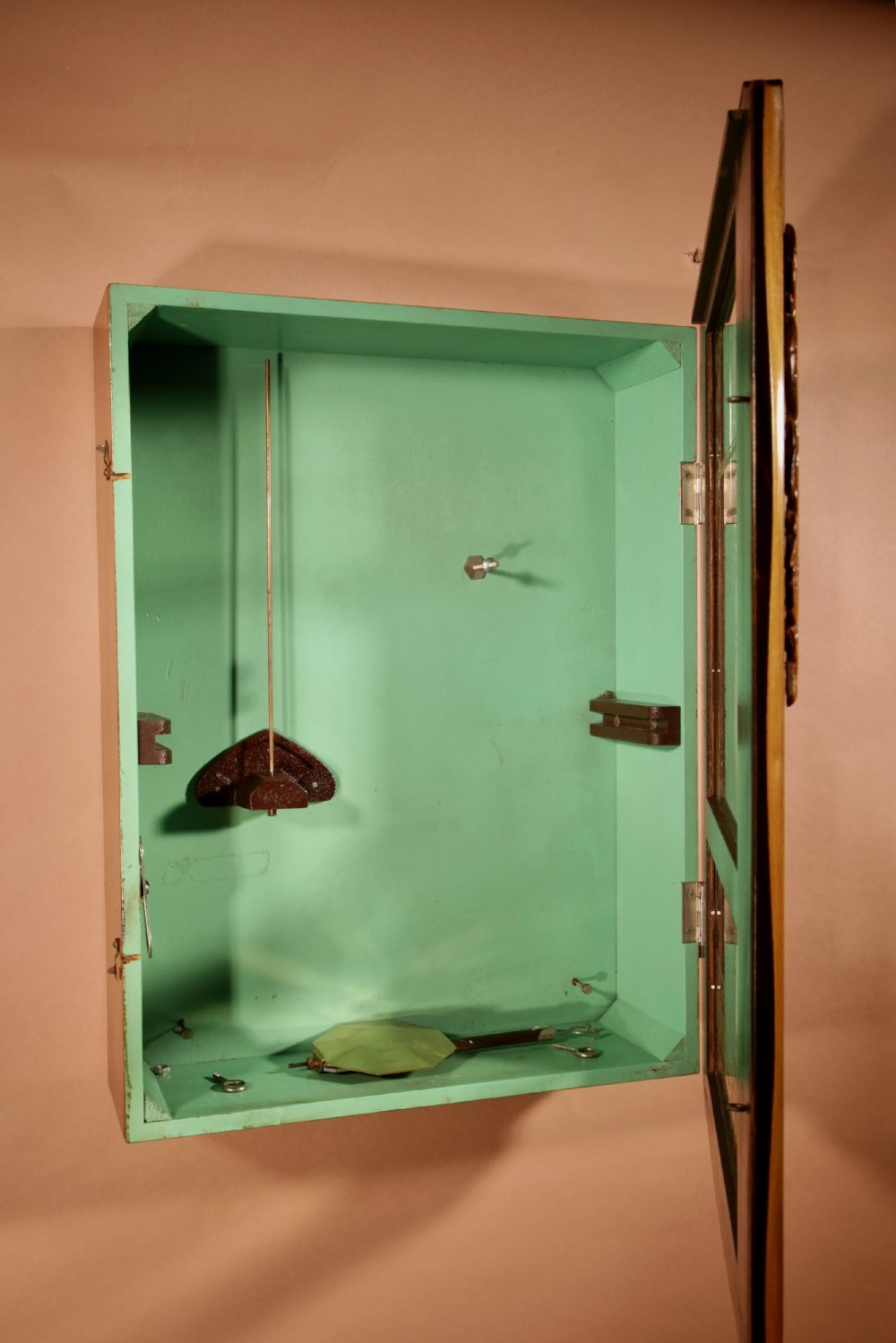 An Art Deco carved walnut wall clock by Odo featuring a brass automaton bell striker and a Venetian glass lower window. View XII