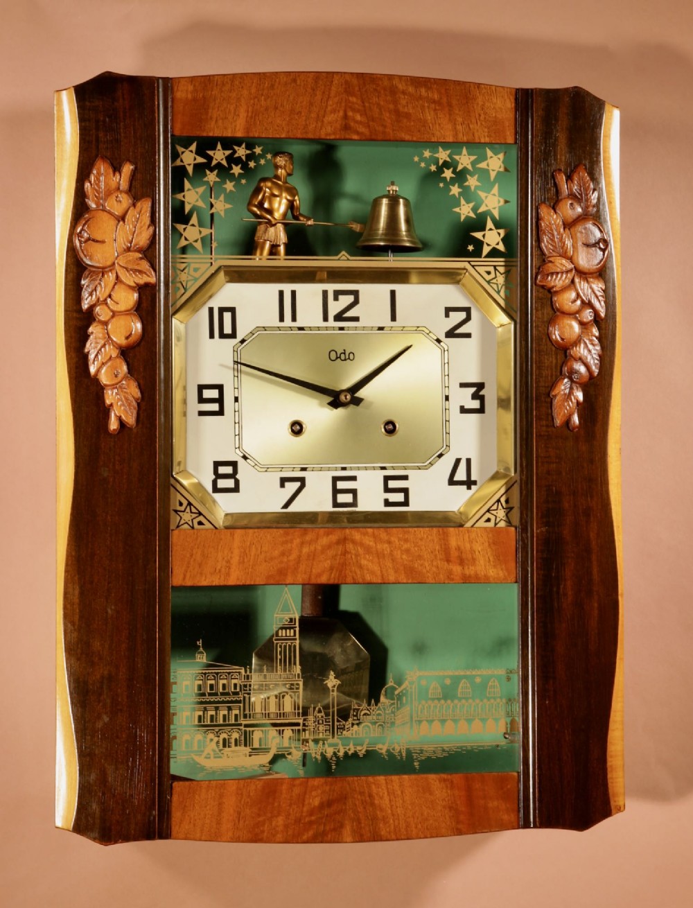 An Art Deco carved walnut wall clock by Odo featuring a brass automaton bell striker and a Venetian glass lower window.