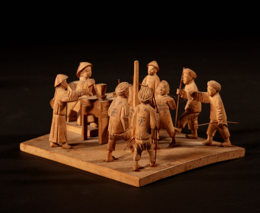 A collection of seven light-coloured Chinese wood carvings depicting figures engaged in traditional daily activities including weaving, fishing, and carrying a sedan chair. View IX