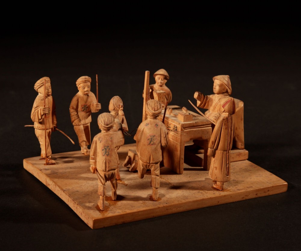 A collection of seven light-coloured Chinese wood carvings depicting figures engaged in traditional daily activities including weaving, fishing, and carrying a sedan chair. View X