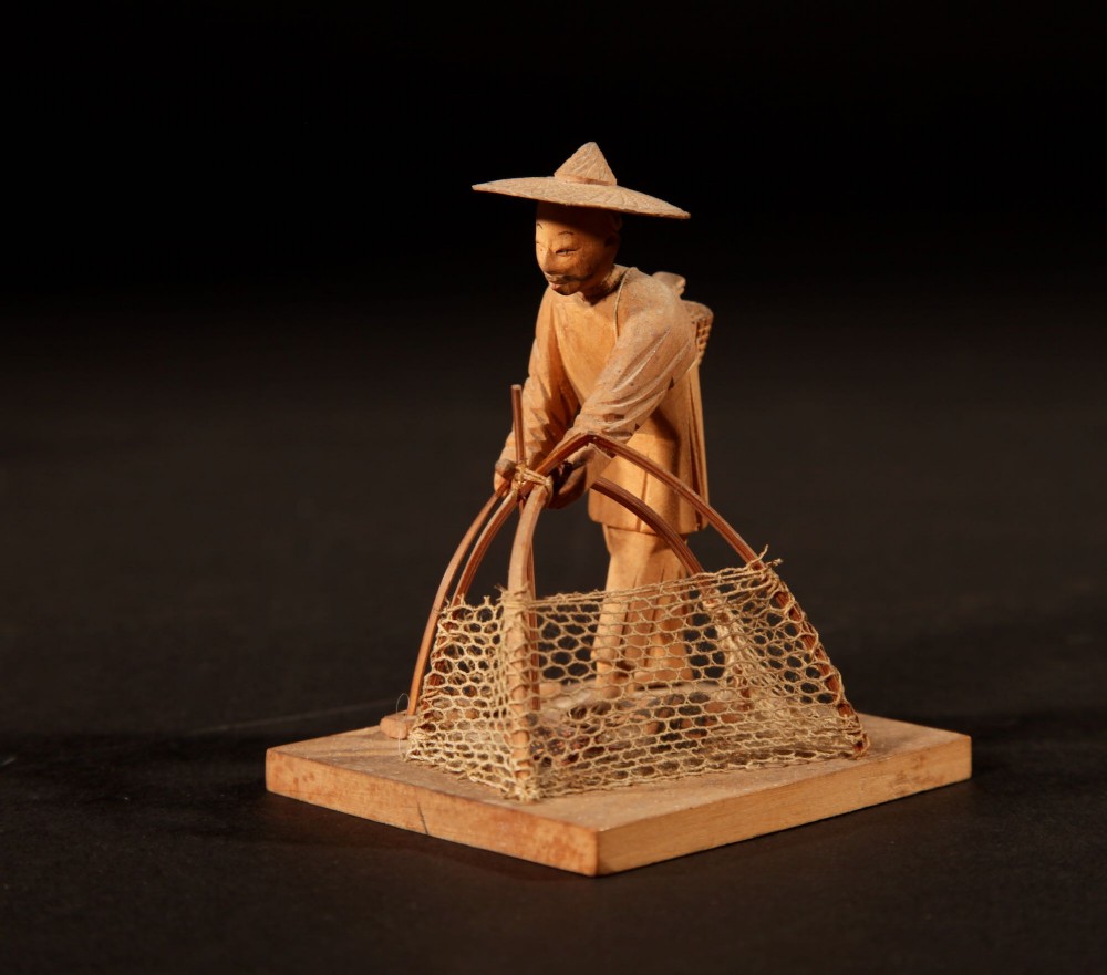 A collection of seven light-coloured Chinese wood carvings depicting figures engaged in traditional daily activities including weaving, fishing, and carrying a sedan chair. View XIII