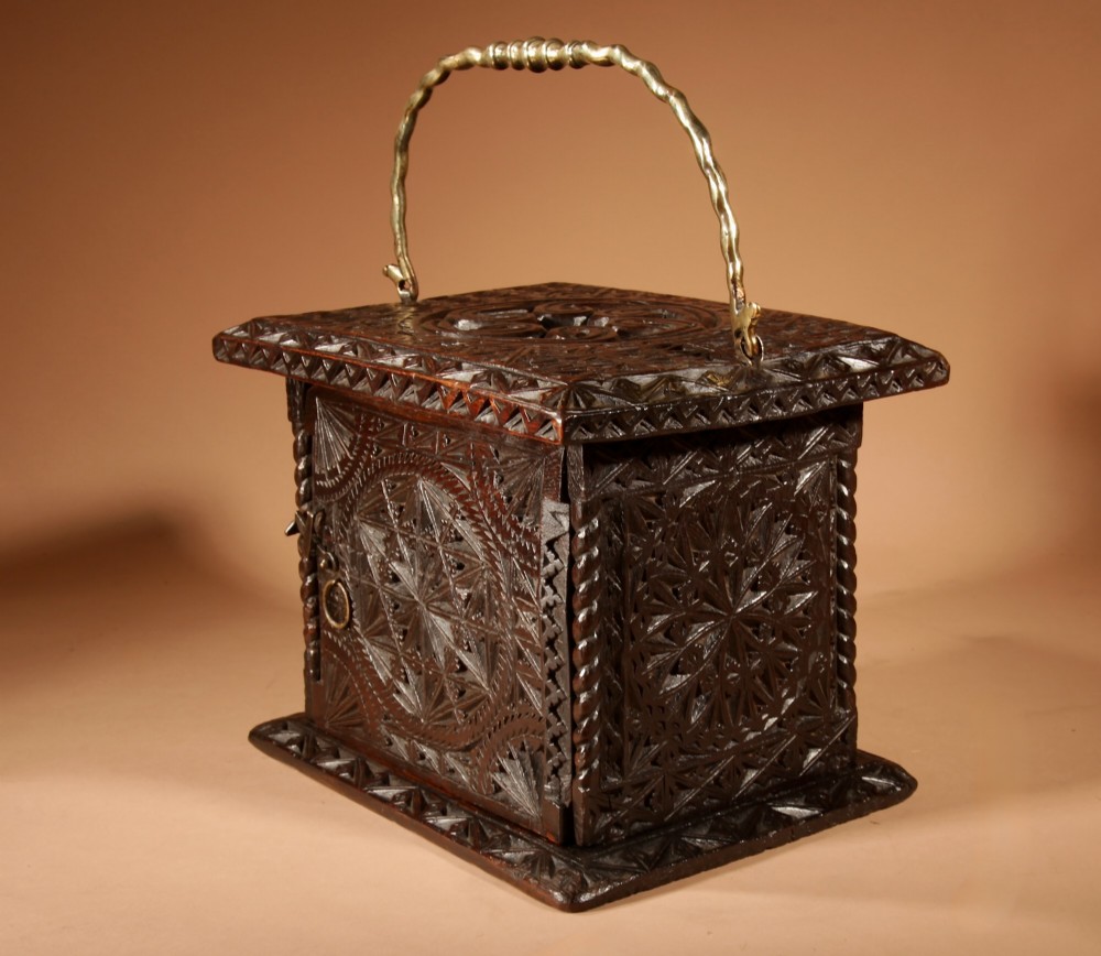 A square dark oak chip-carved foot stove with a hinged door, geometric rosette carvings, and a brass swing handle. View IV