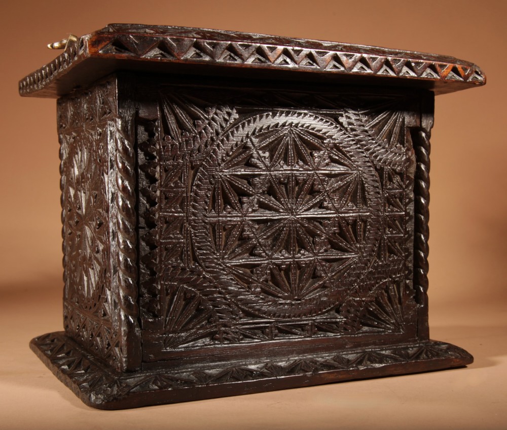 A square dark oak chip-carved foot stove with a hinged door, geometric rosette carvings, and a brass swing handle. View VI