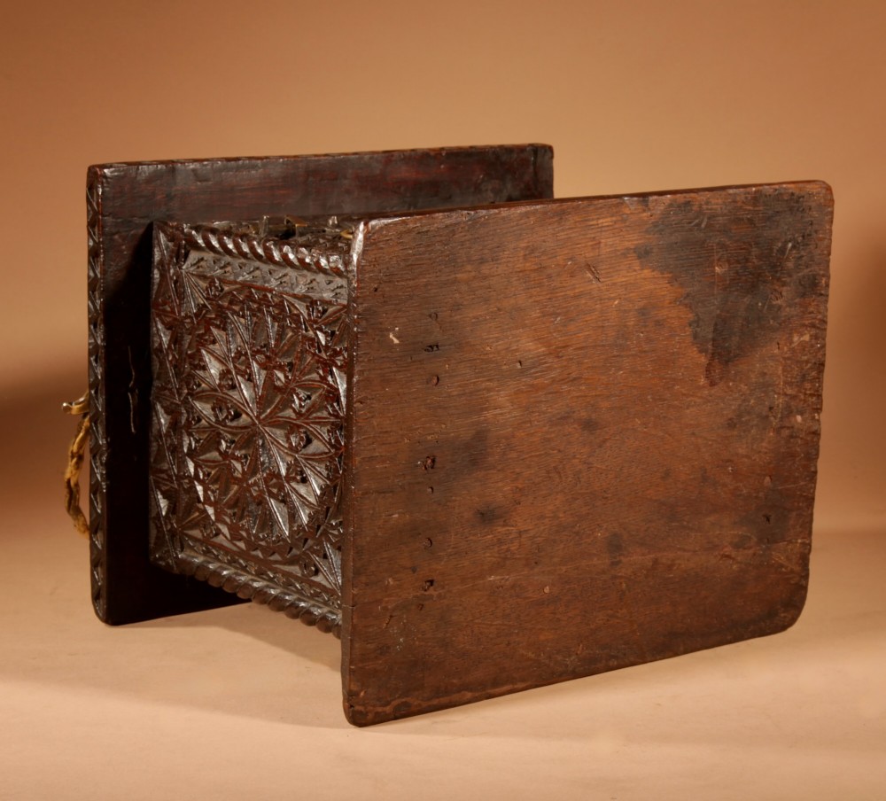 A square dark oak chip-carved foot stove with a hinged door, geometric rosette carvings, and a brass swing handle. View VIII