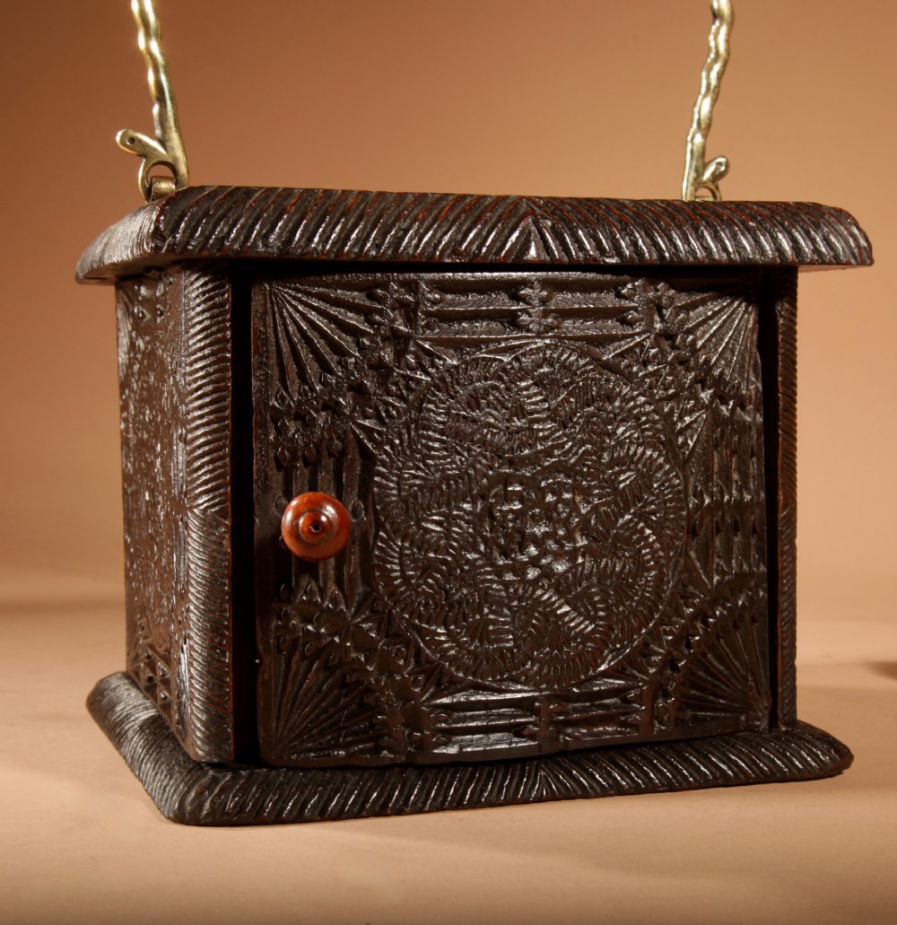 A dark oak foot stove featuring geometric chip carving and a twisted brass handle. View II
