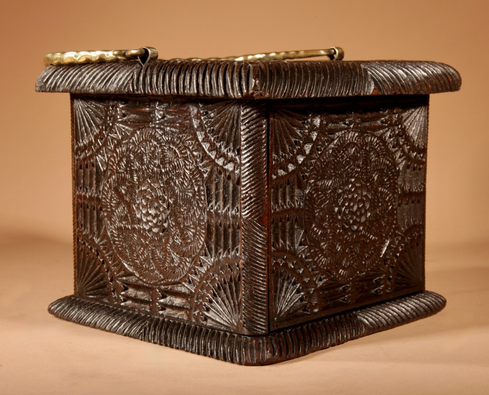 A dark oak foot stove featuring geometric chip carving and a twisted brass handle. View IV