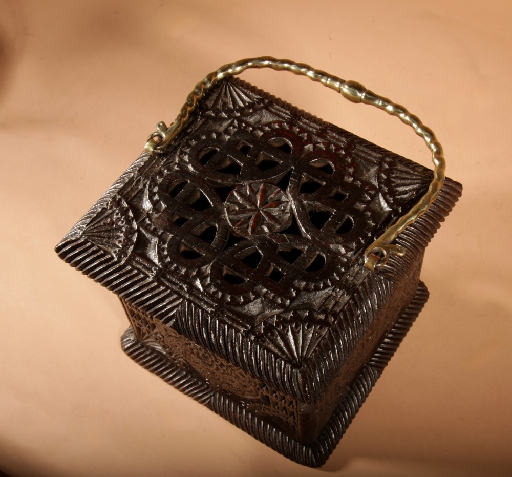 A dark oak foot stove featuring geometric chip carving and a twisted brass handle. View V