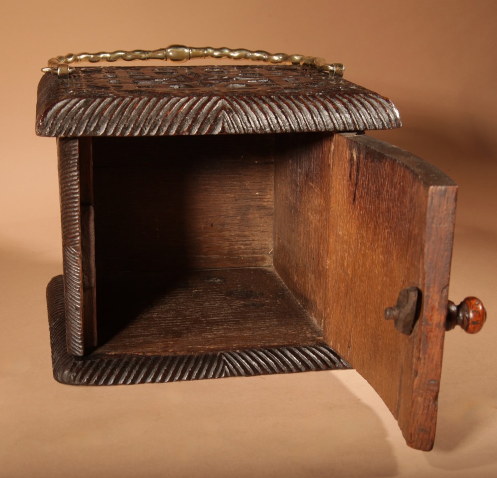 A dark oak foot stove featuring geometric chip carving and a twisted brass handle. View VII