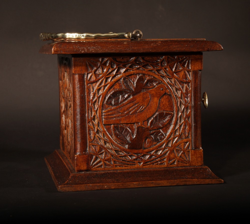 A square chip-carved wooden foot stove dated 1901 featuring relief carvings of animals and a brass carrying handle. View V