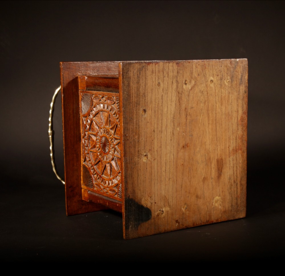 A square chip-carved wooden foot stove dated 1901 featuring relief carvings of animals and a brass carrying handle. View VI