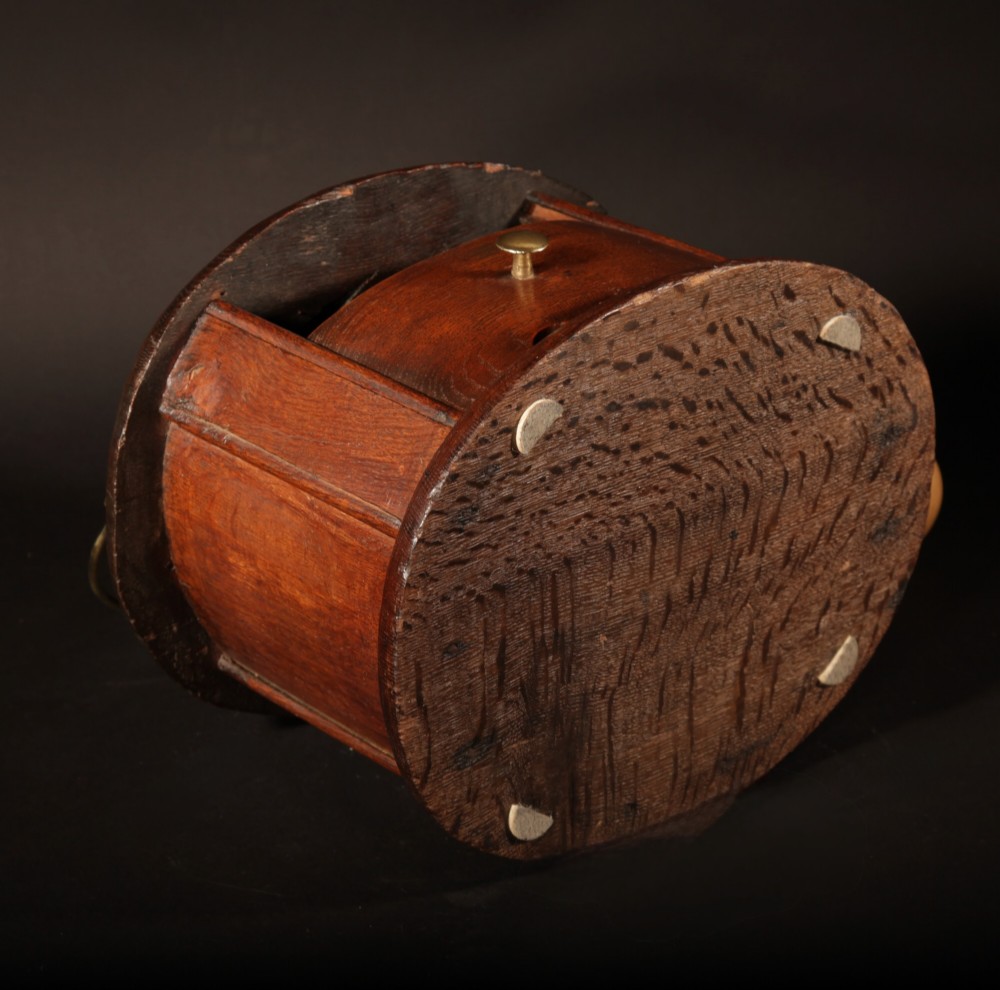 An oval dark oak foot stove featuring a carved geometric top aperture and an arched brass carrying handle. View IV