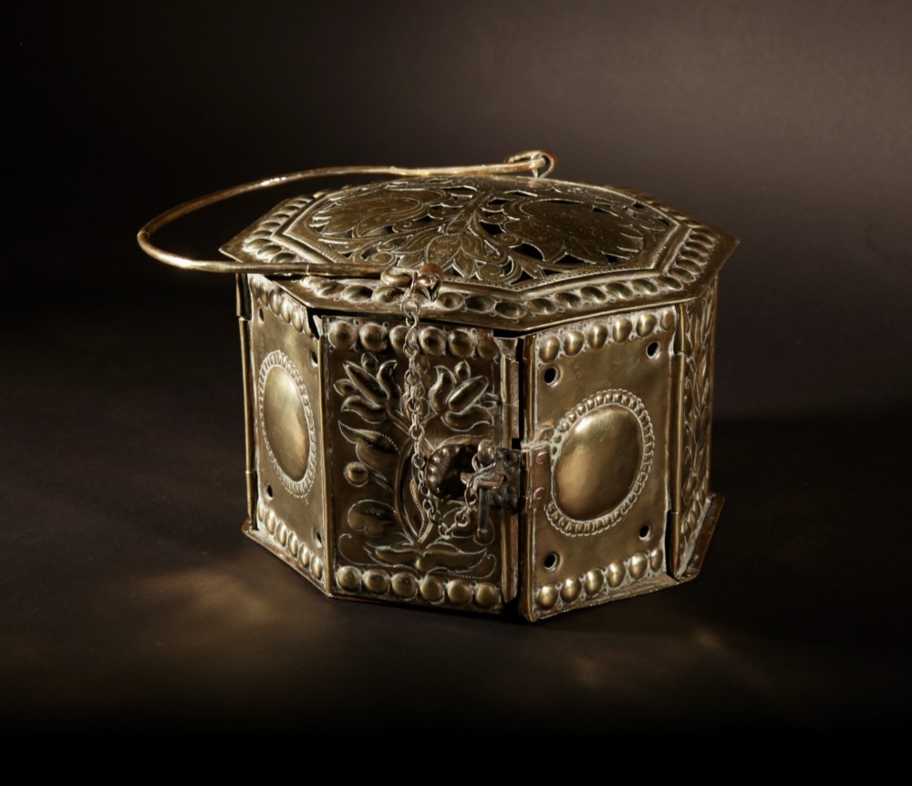 An 18th-century octagonal brass foot stove featuring hand-embossed floral panels, a pierced lid, and an overhead carrying handle. View II