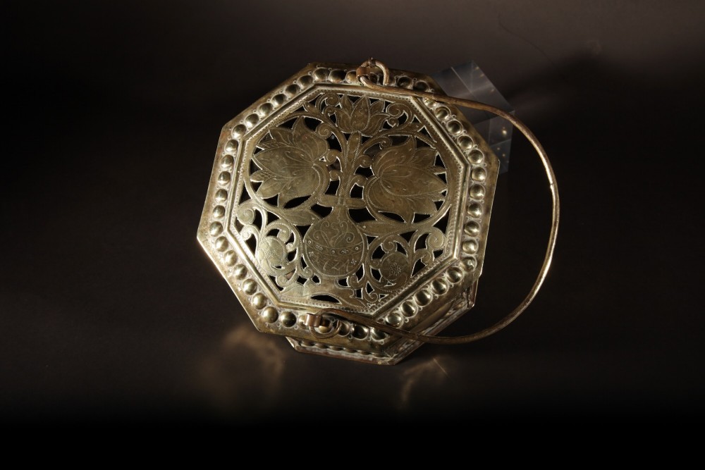 An 18th-century octagonal brass foot stove featuring hand-embossed floral panels, a pierced lid, and an overhead carrying handle. View III