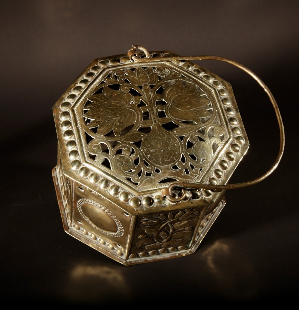 An 18th-century octagonal brass foot stove featuring hand-embossed floral panels, a pierced lid, and an overhead carrying handle. View XI