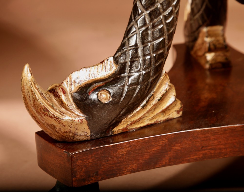 A French Empire mahogany slatted wine cooler featuring a brass liner and supported by three carved ebonised dolphin legs on a triform base with paw feet. View V