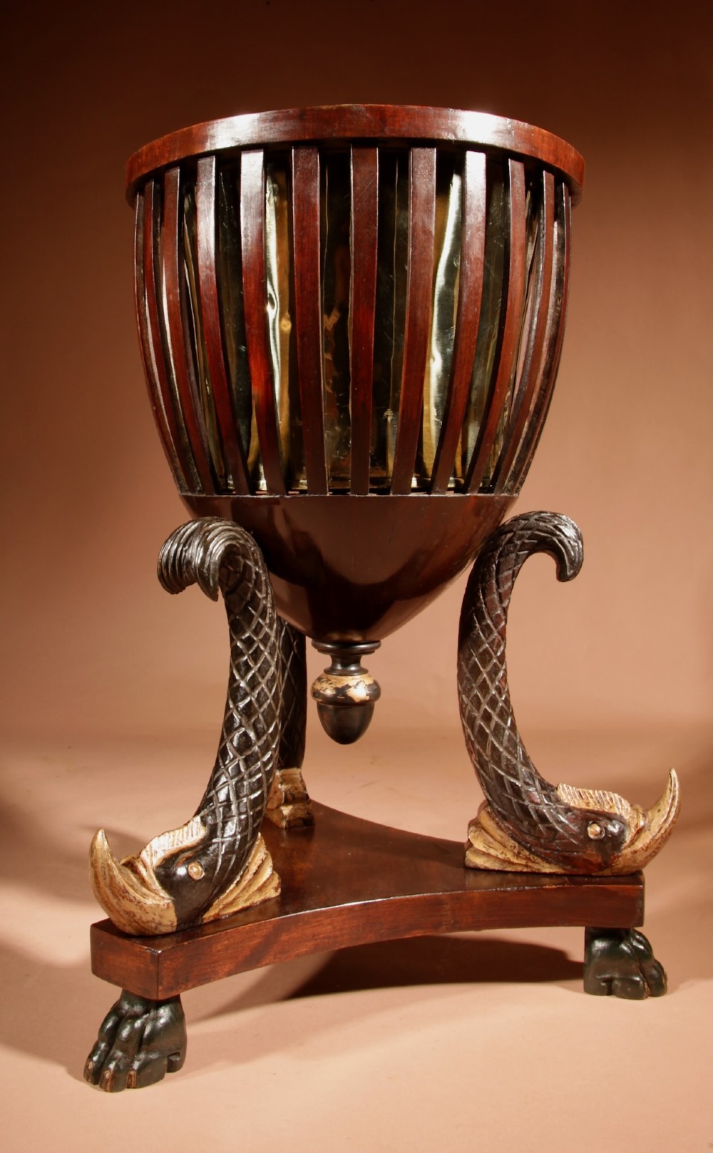 A French Empire mahogany slatted wine cooler featuring a brass liner and supported by three carved ebonised dolphin legs on a triform base with paw feet. View VI