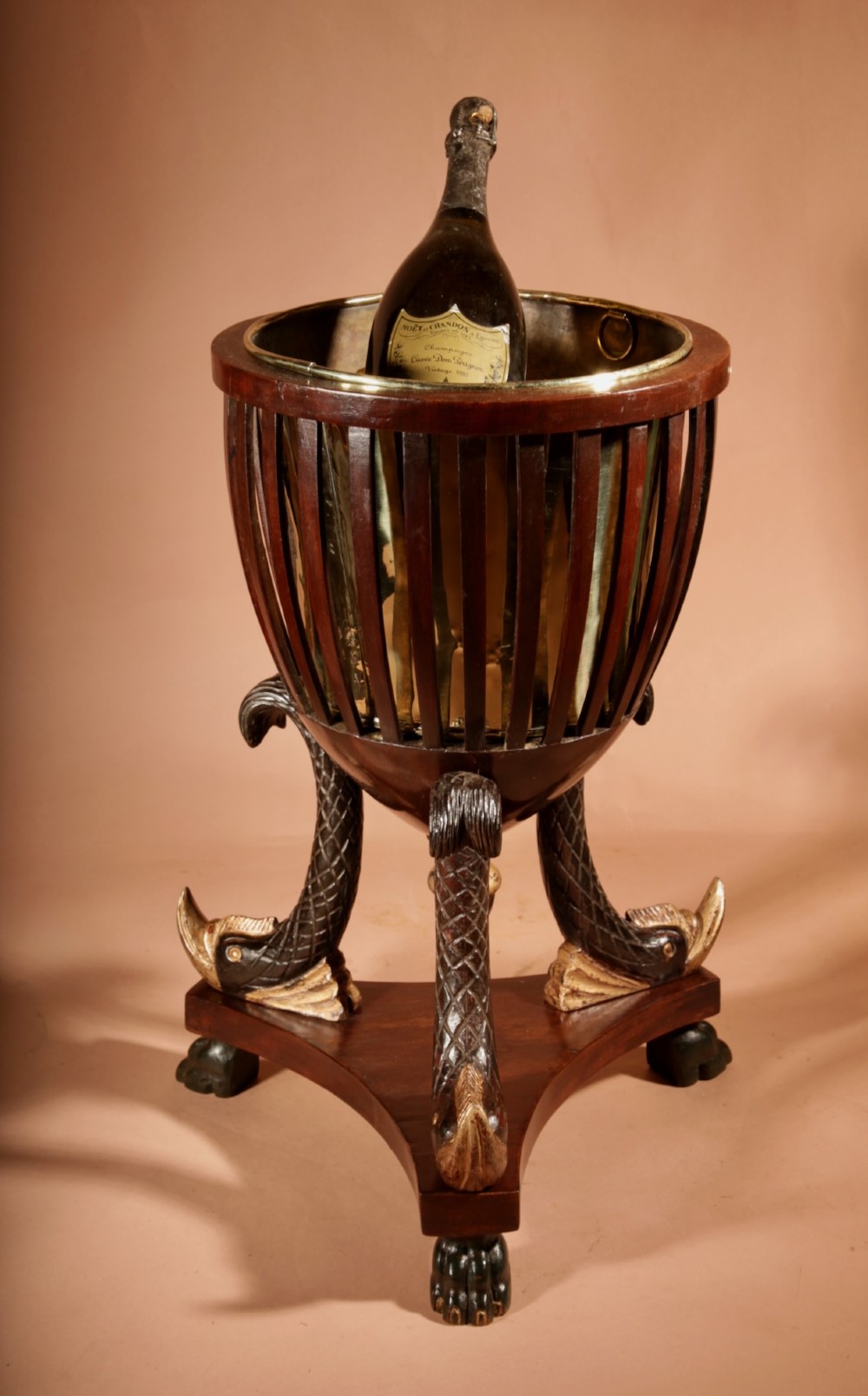 A French Empire mahogany slatted wine cooler featuring a brass liner and supported by three carved ebonised dolphin legs on a triform base with paw feet. View XI