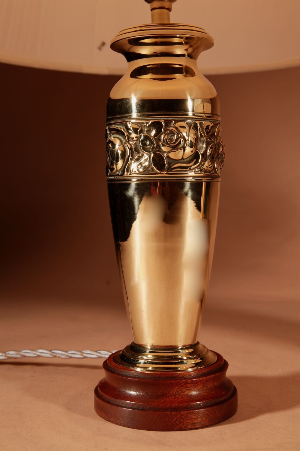 A pair of French Art Deco polished brass urn-form table lamps featuring embossed floral bands on wooden bases with pleated cream shades. View VI