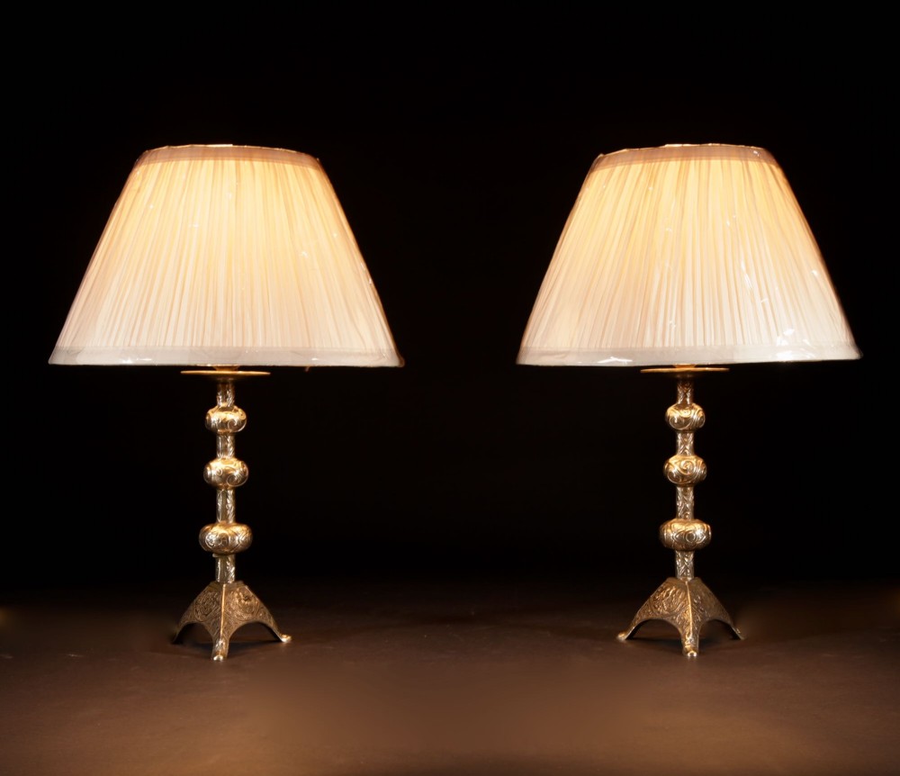 A pair of gold brass table lamps featuring relief-patterned shafts, tripod bases, and cream pleated shades. View II
