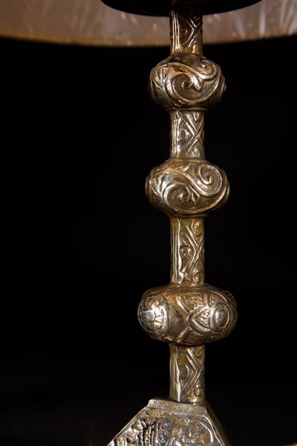 A pair of gold brass table lamps featuring relief-patterned shafts, tripod bases, and cream pleated shades. View VII
