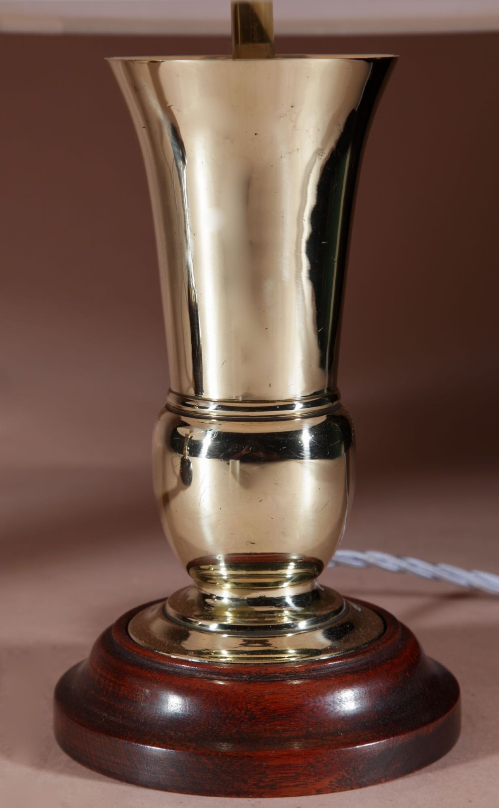 A pair of flared brass vase-form table lamps on circular dark wood bases with off-white pleated shades. View V