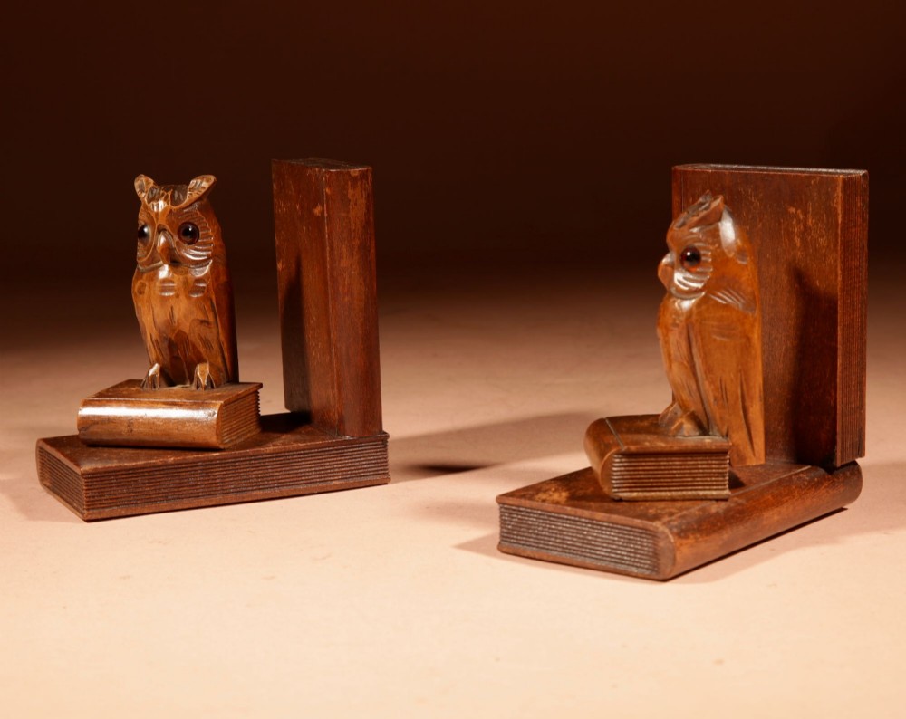 A pair of hand-carved wooden bookends featuring owls with glass eyes perched on carved book bases. View X