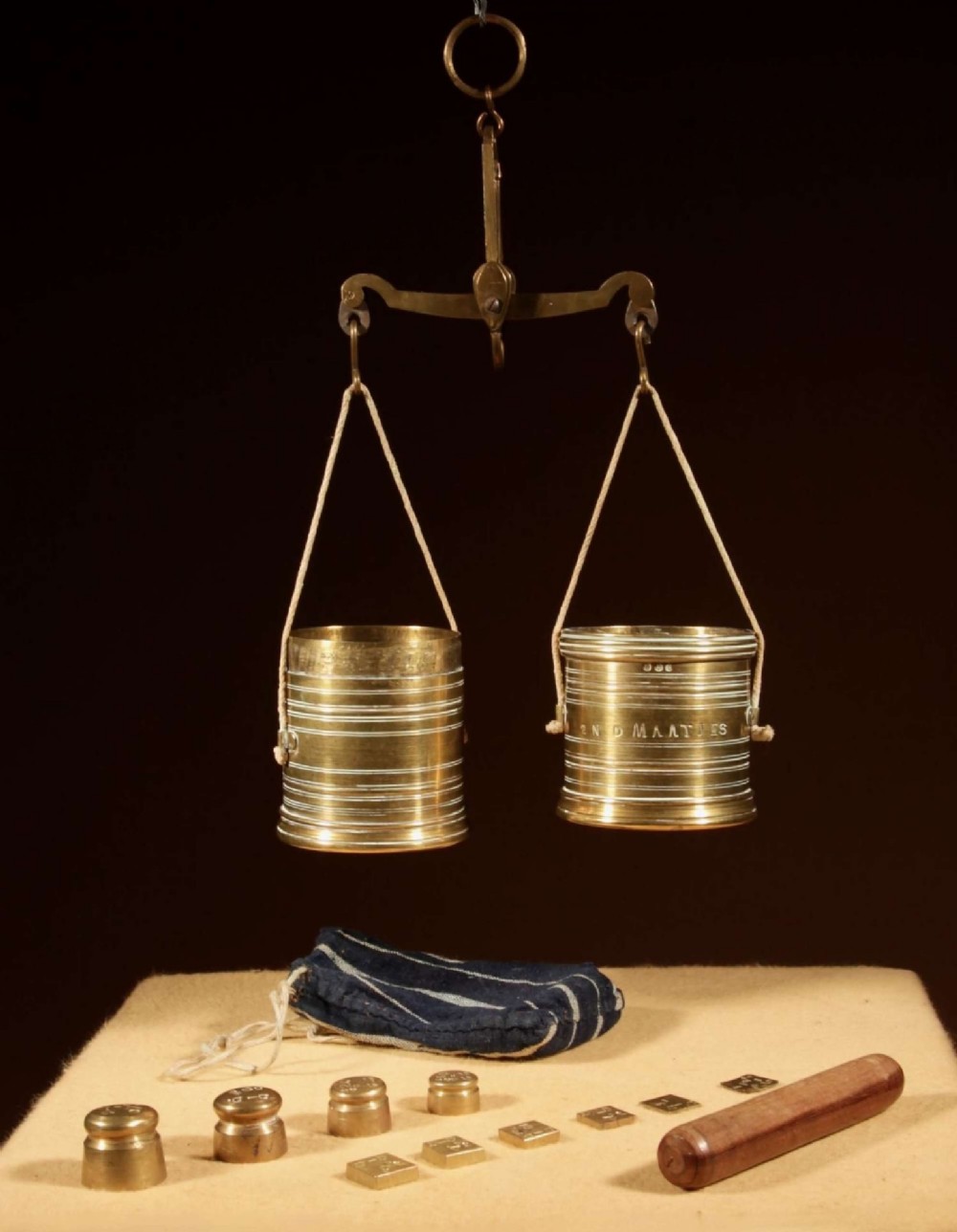 An 1846 Dutch brass bushel balance set featuring a balance beam, two cylindrical brass measuring buckets, calibrated brass weights, a wooden striker, and a striped fabric pouch. View II